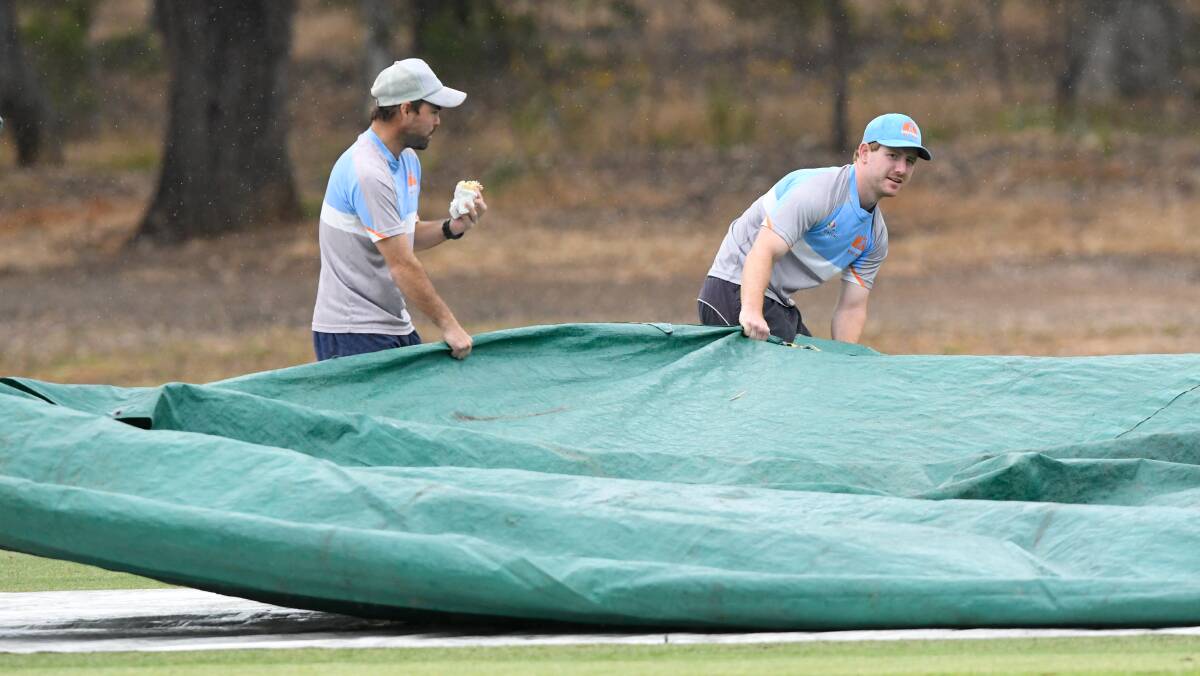 WASHOUT: Strathdale-Maristians' players Linton Jacobs and Daniel Clohesy help put the covers on Bell Oval on Saturday. Picture: NONI HYETT