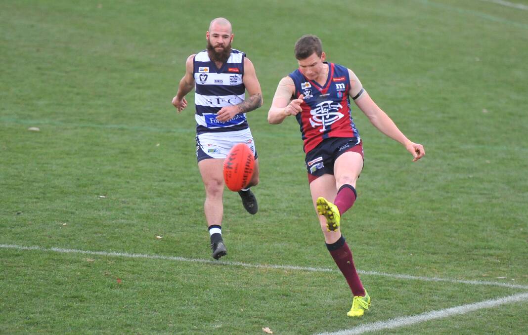 CLASS ACT: Sandhurst coach Andrew Collins gets a kick away in front of Strathfieldsaye's Josh Formosa on Saturday. Collins bagged six goals in the Dragons' impressive 46-point win at the QEO. The Dragons kicked 13.10 to 3.8 after quarter-time. Picture: LUKE WEST