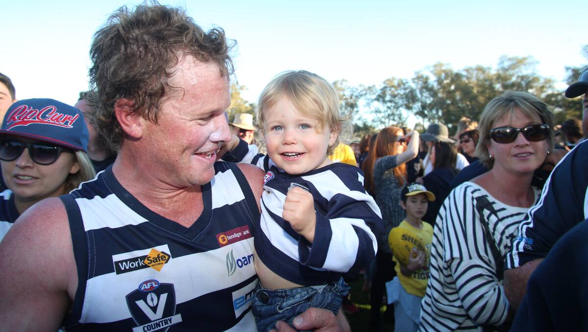 GRAND DAY: Mick Dobson celebrates LBU's 2014 grand final win with son Jude. Dobson played in all four of the Cats' flags between 2011 and 2014.