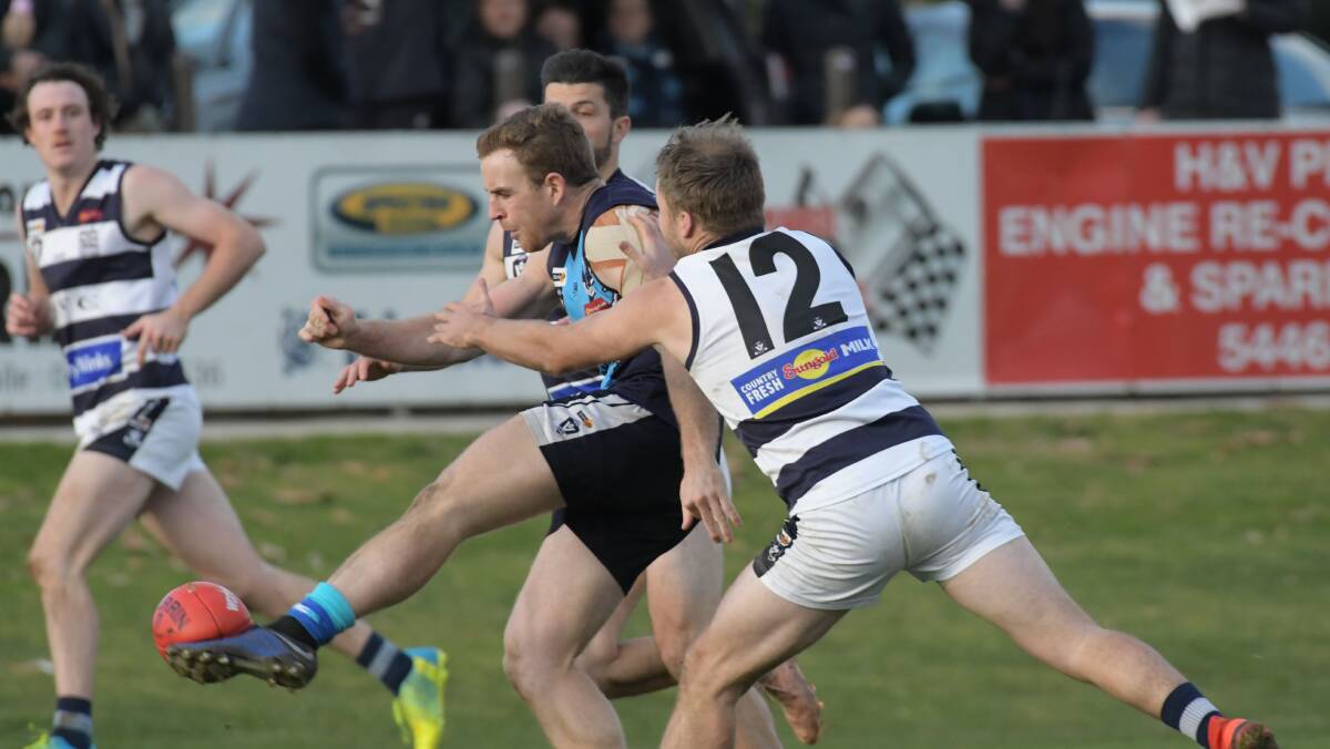 HAWK ON THE ATTACK: Eaglehawk's Ben McPhee gets a kick away in front of Strathfieldsaye's Shannon Geary on Saturday. The Hawks inflicted the Storm's first loss of the BFNL season with their 18-point win at Canterbury Park. Picture: NONI HYETT