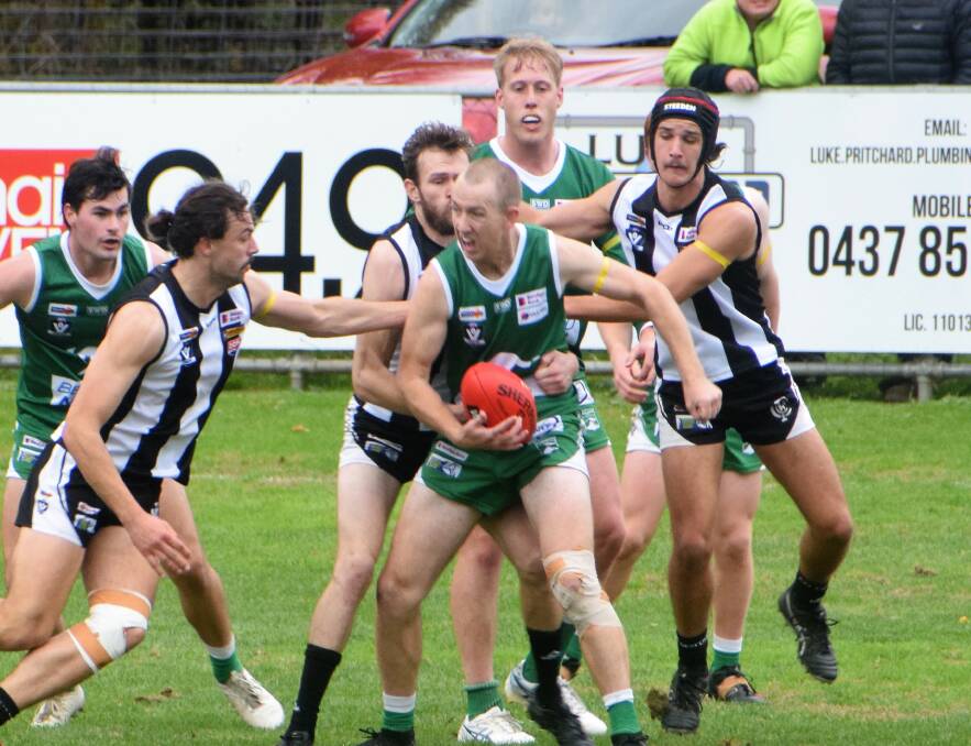 CONTESTED BALL: Kangaroo Flat's Mitch Collins, who hurt his knee during the game, with possession among a nest of Castlemaine players at Camp Reserve on Saturday. The Roos kicked away after half-time to win by 38 points. Picture: KIERAN ILES