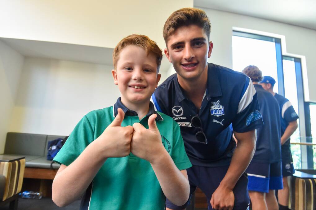 North Melbourne supporter Fletcher Hartrey with the Kangaroos' Harry Sheezel on Monday. Picture by Darren Howe
