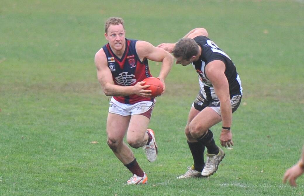 ON THE BURST: Sandhurst captain Blair Holmes gets around Castlemaine's James O'Brien in the last quarter at Camp Reserve on Saturday. Picture: LUKE WEST