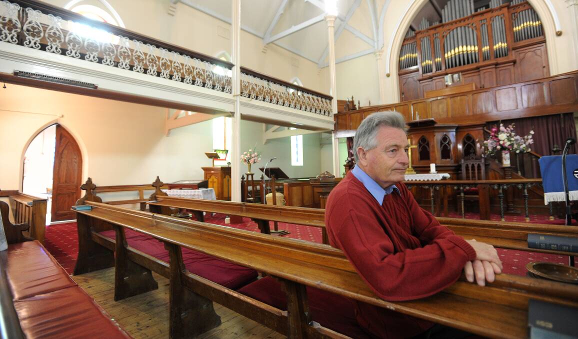 ORIGINAL PEWS: Former parishioner and organist David Wright pictured on the pews in 2013 when the Golden Square Uniting Church was first put to market. 