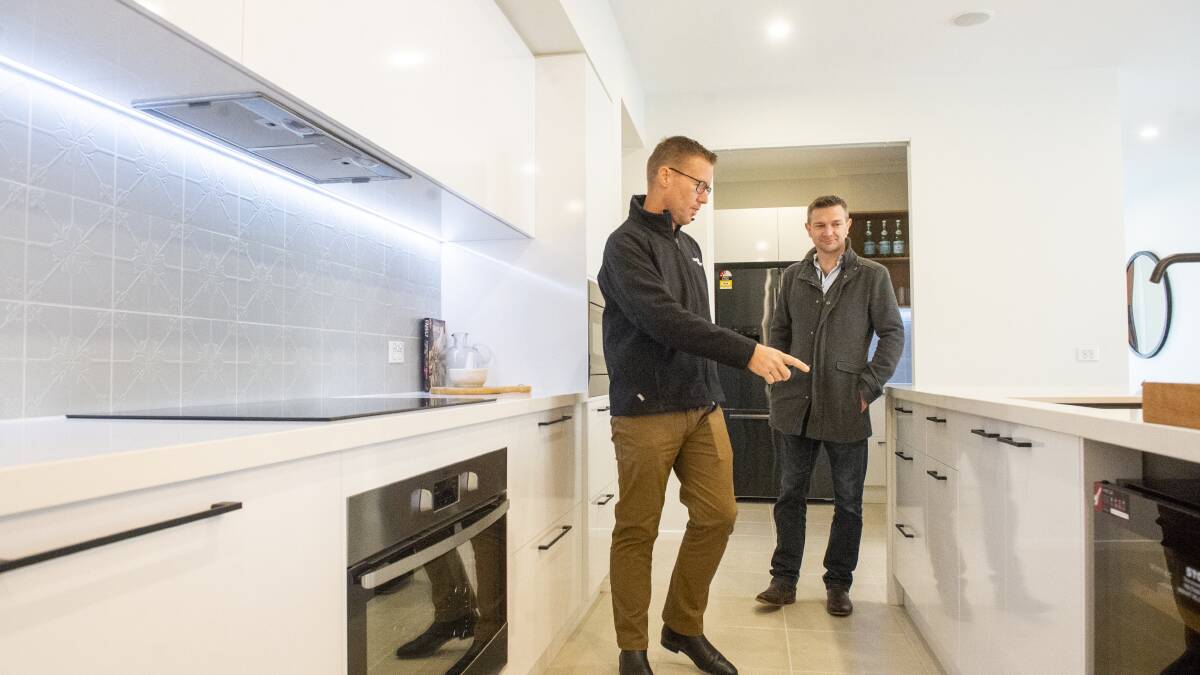 BUSINESS BOOMING: Local builder Leigh Moore discusses home options with one of several new customers, Travis Breheny. Picture: DARREN HOWE