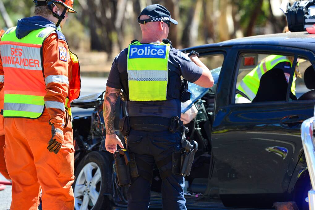 A police officer inspects a car involved in a crash. Picture by Darren Howe