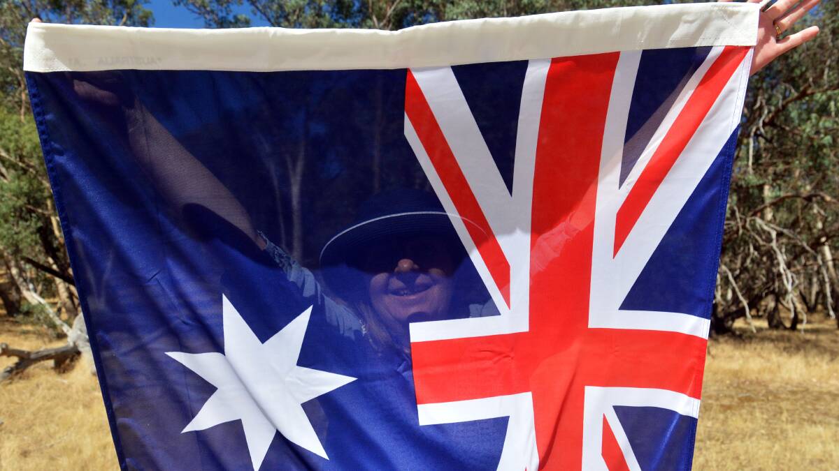 A central Victorian unfurls a flag prior to it being run up the flag pole for Australia Day celebrations. Picture: Brendan McCarthy