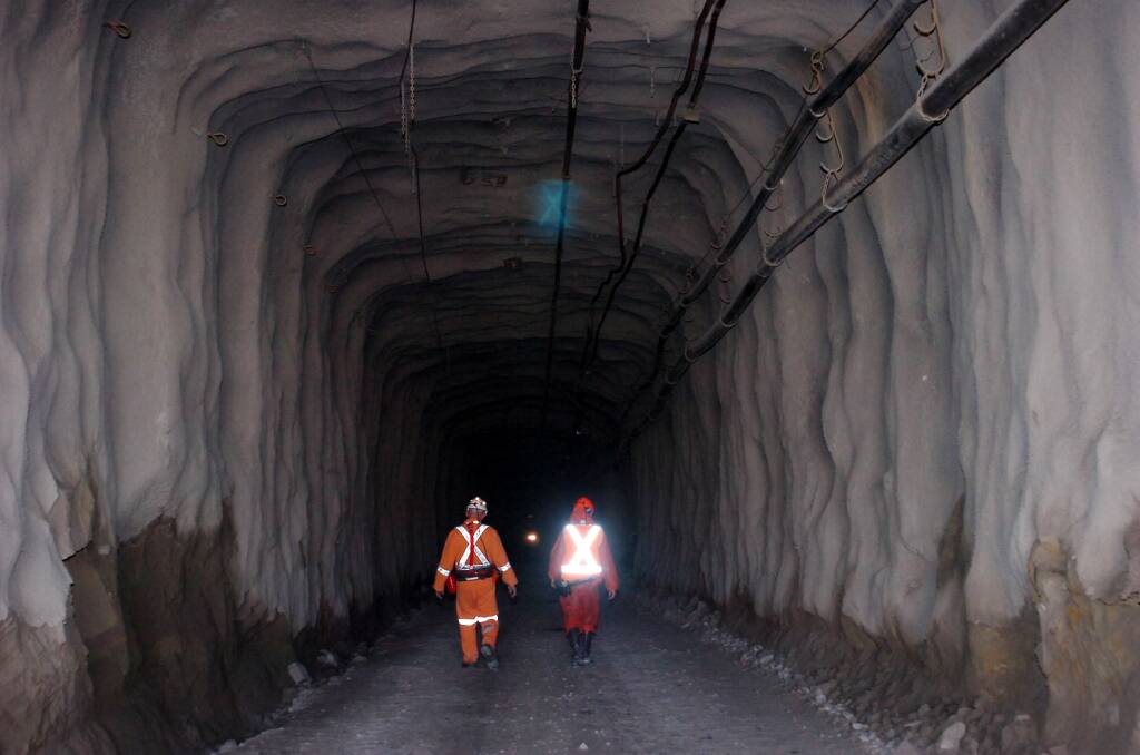 INTO THE DEEP: Miners walk into the darkness on a road just inside the Swan Decline. Picture: LAURA SCOTT
