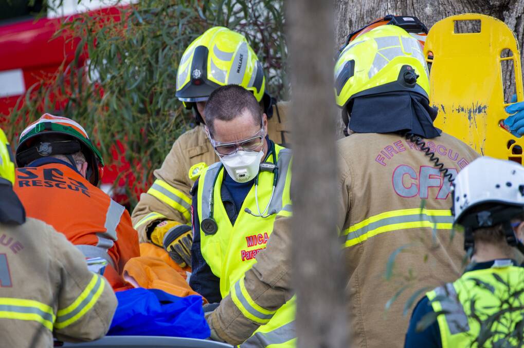 CFA and SES crews help a paramedic remove a man from his car. Picture: DARREN HOWE