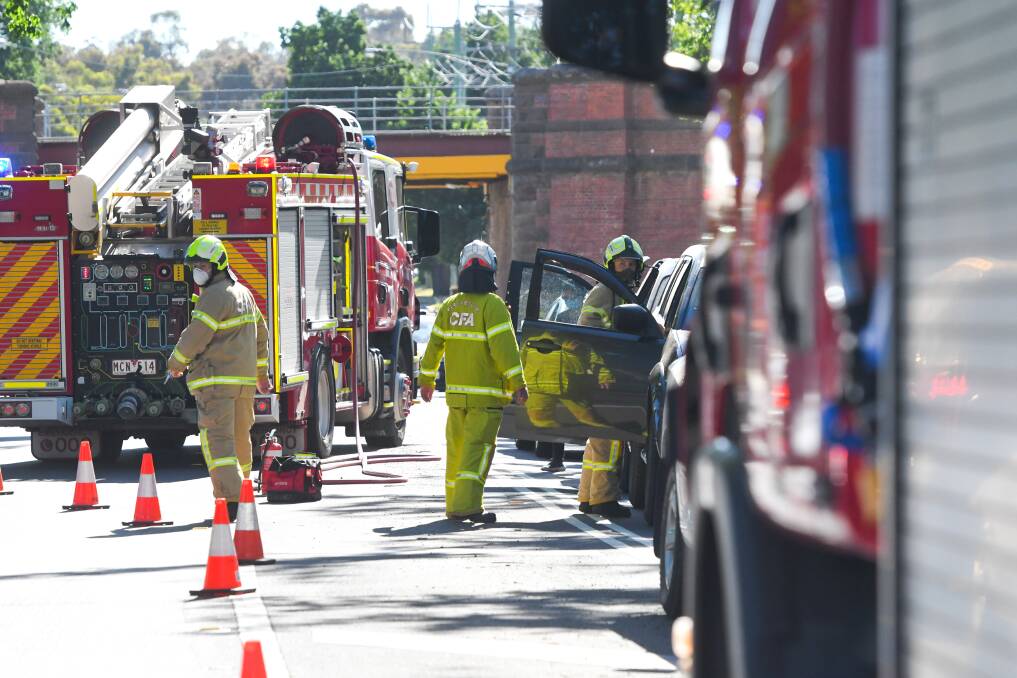 Emergency services direct traffic and see to someone in a car following a McIvor Road car crash. Picture: NONI HYETT