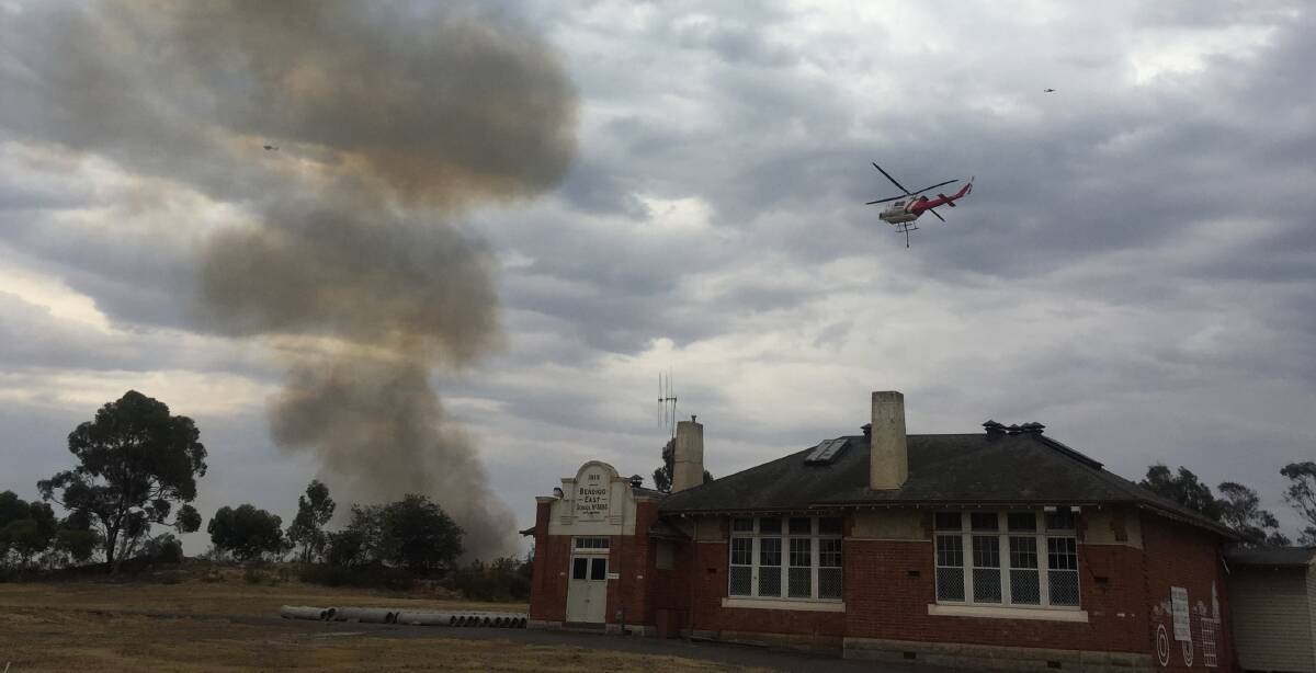A helicopter prepares to drop water on a fire in Bobs Street, White Hills. Picture: ELSPETH KERNEBONE