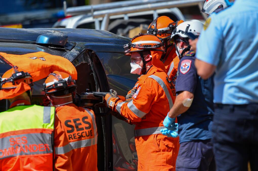 A Castlemaine SES crew member helps drill a hole in the roof of a flipped car in Sutton Grange. It was part of an operation to free a man trapped following a crash. Picture: DARREN HOWE