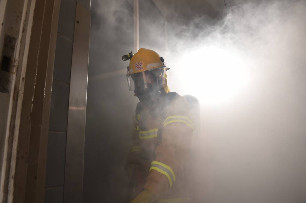 A firefighter in full breathing gear inspects a room filled with smoke. Picture by Noni Hyett.