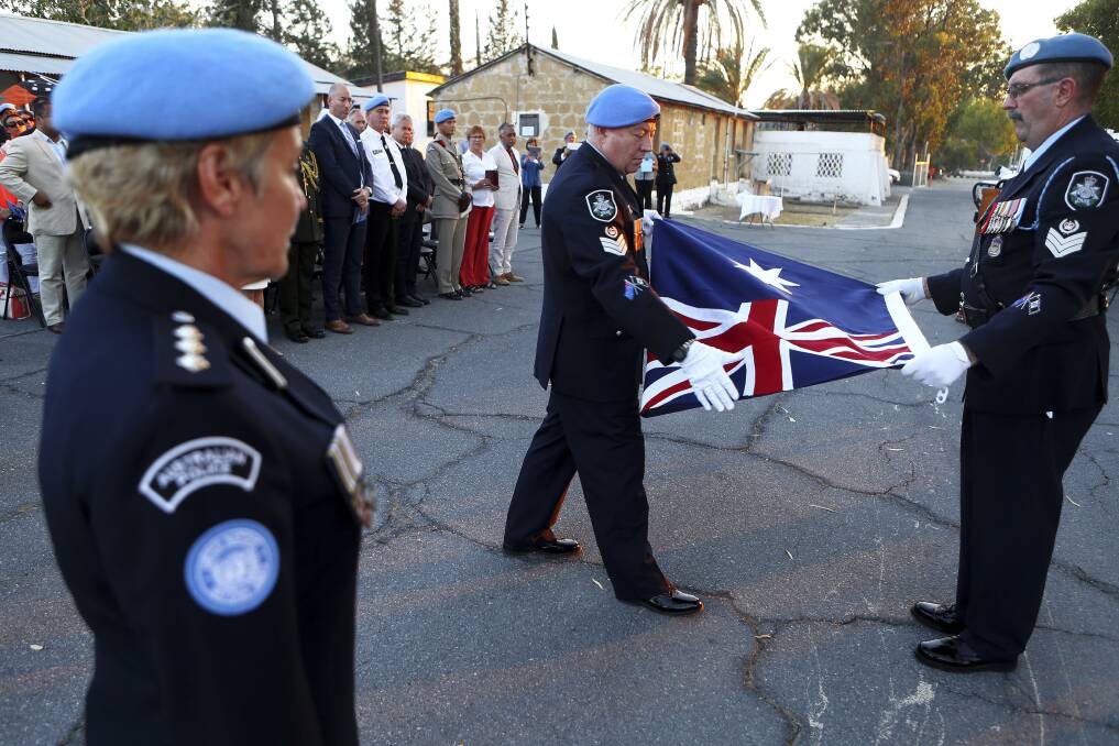 An Australian U.N police officer fold the Australian flag during a flag-lowering ceremony to end the nation's peacekeeping contribution in Cyprus in June, 2017. Picture: AP Photo/Petros Karadjias