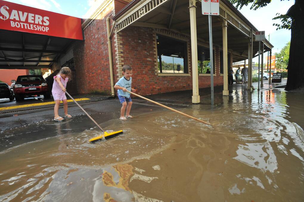 COUNTING THE COSTS: Ella and Cooper Russell help clear the last of the water away from The National Hotel in Golden Square, following a 2011 flash flood. Picture: PETER WEAVING