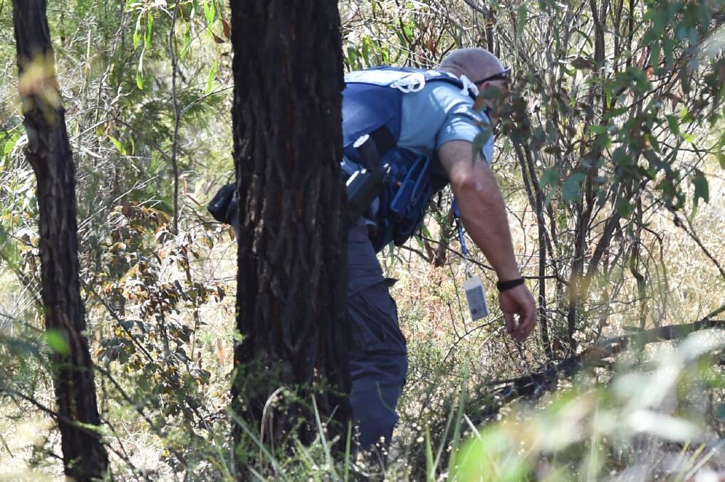 A police officer searching bushland. Picture is a file photo by Darren Howe.