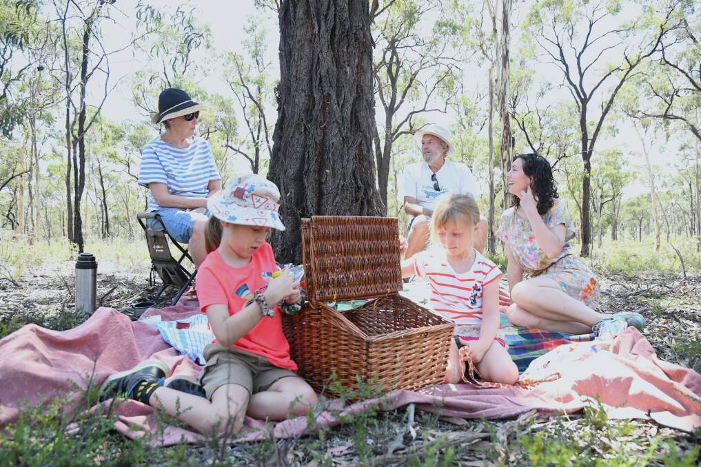 Chloe and Lucy Abel explore a picnic basket while mother Mel and friends John Bardsley and Wendy Radford discuss the Wellsford Forest's future. Picture: TOM O'CALLAGHAN