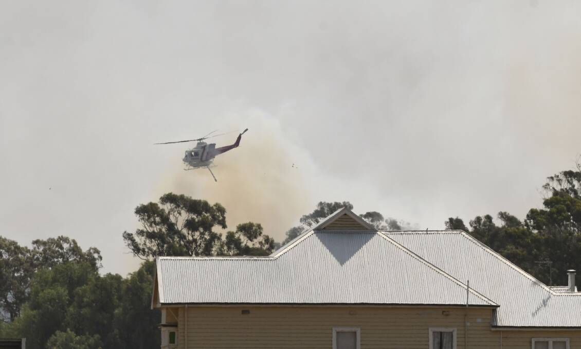 A helicopter drops water on a fire burning out of control in Huntly. Picture: NONI HYETT