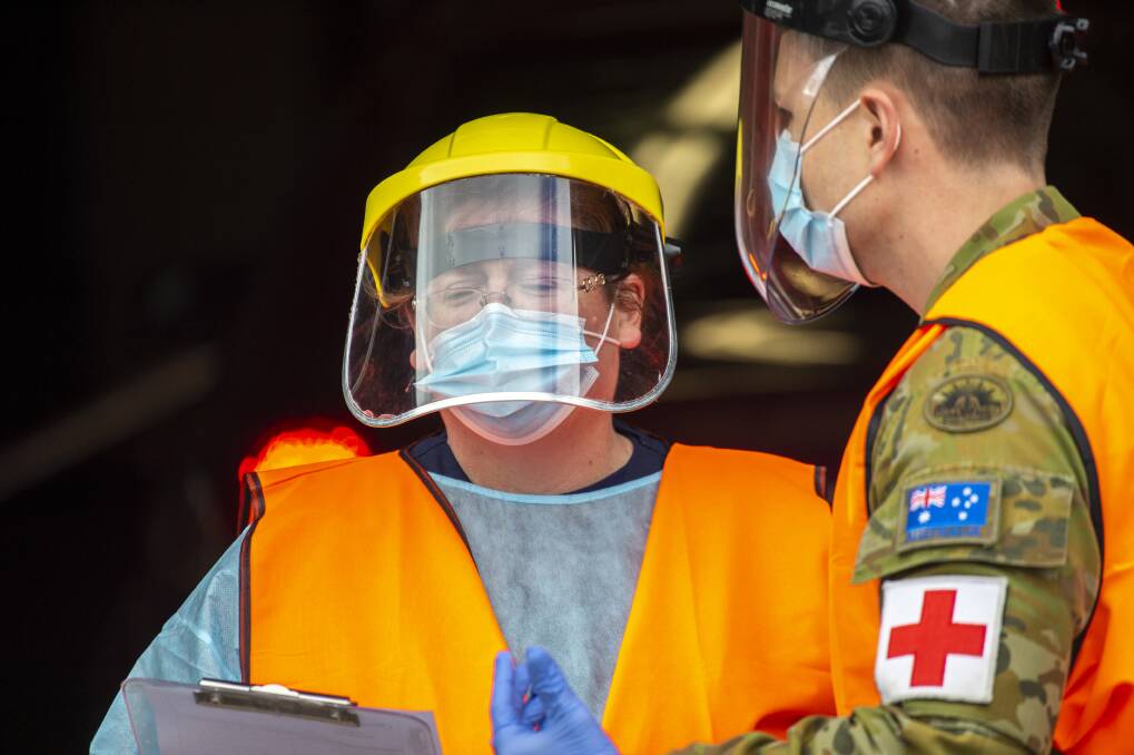 An ADF member talks with a Bendigo Health worker after being deployed to a central Victorian COVID-19 testing site late last month. Picture: Darren HOWE