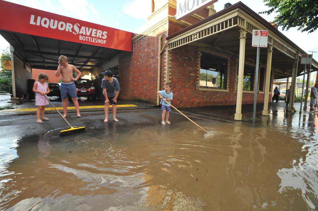 COUNTING THE COSTS: Ella and Cooper Russell help clear the last of the water away from The National Hotel in Golden Square, following a 2011 flash flood. Picture: PETER WEAVING