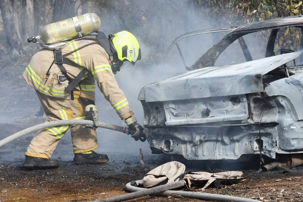 FIRES: A CFA member helps put out a car fire. Police say they have been called to three already this month. Picture: DARREN HOWE