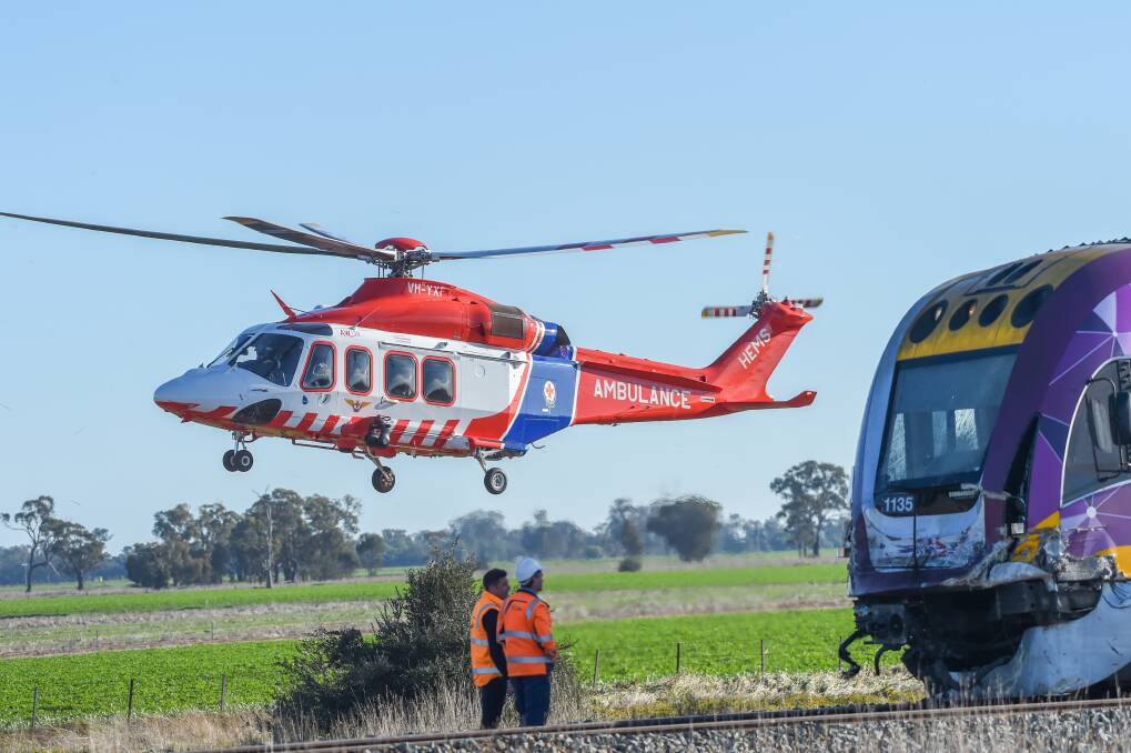 People at the Goornong crash scene survey the damage to a train as a truck driver is airlifted to a Melbourne hospital. Picture by Darren Howe