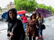 A group of people brave the wet weather in Bendigo. Picture Enzo Tomasiello