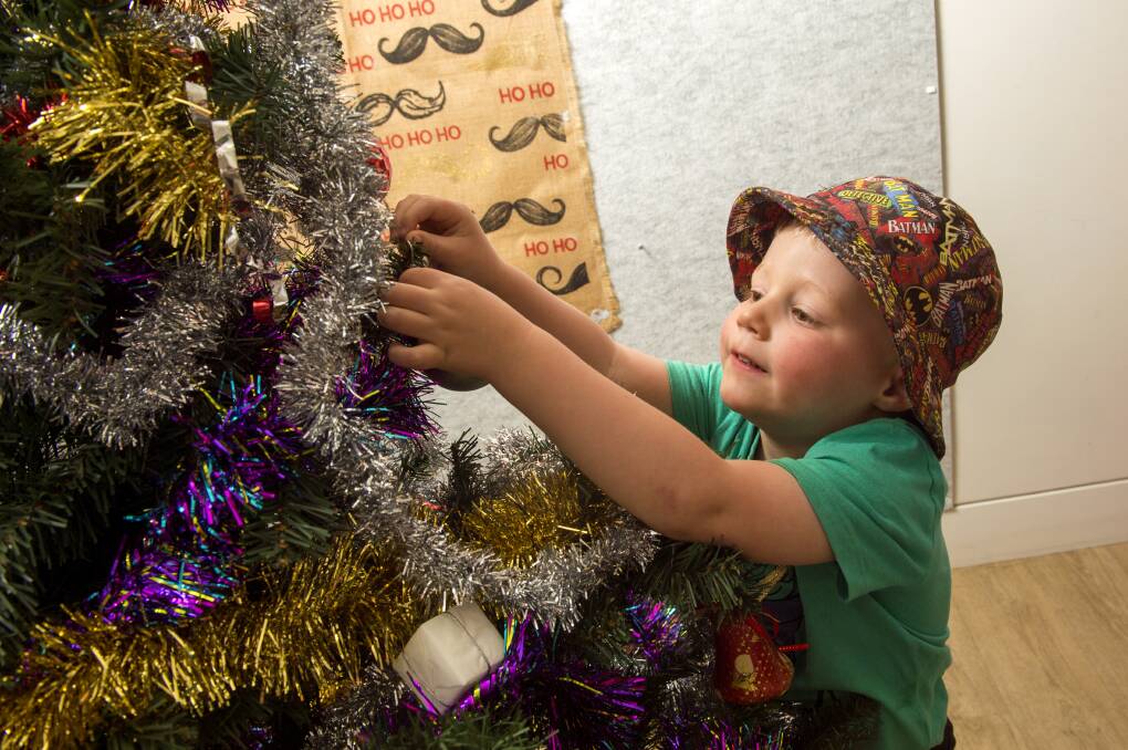DECORATIONS: Hamish Madden puts decorations on a Christmas tree. Picture: DARREN HOWE