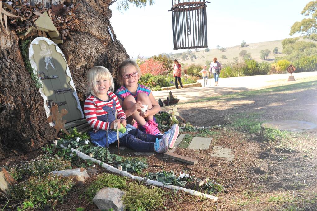 ALL SMILES: Chloe and Rhiannon play in the fairy garden under a magical tree at Mica Grange Open Scupture Garden. Picture: NONI HYETT