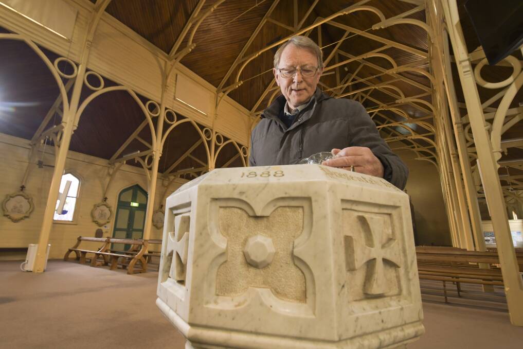 Fr Rom Hayes at the marble baptismal font. Picture: NONI HYETT