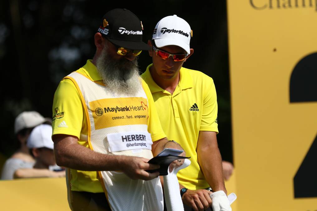 Lucas Herbert and his caddie go over yardages on the second tee during round three of the Maybank Championship. Picture: AP/Vincent Phoon