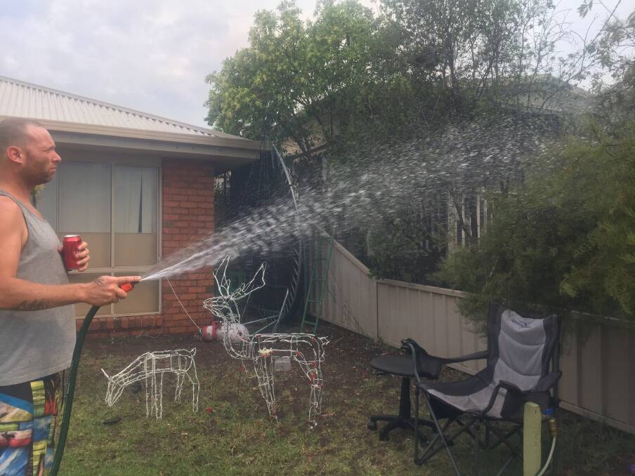 James Ashdown hoses down the front of his Strickland Road house. Picture: ELSPETH KERNEBONE