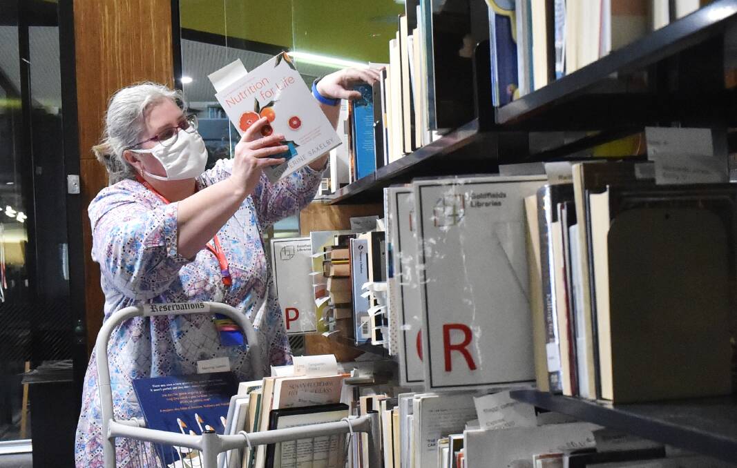 PAGE TURNERS: Librarian Leanne retrieves books requested by people as part of the Goldfields Libraries' Reserve and Collect program. Picture: DARREN HOWE