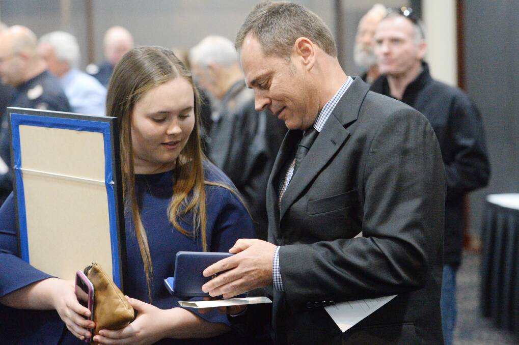 Detective Leading Senior Constable Matthew Goss shows his awards to his daughter. Picture: DARREN HOWE