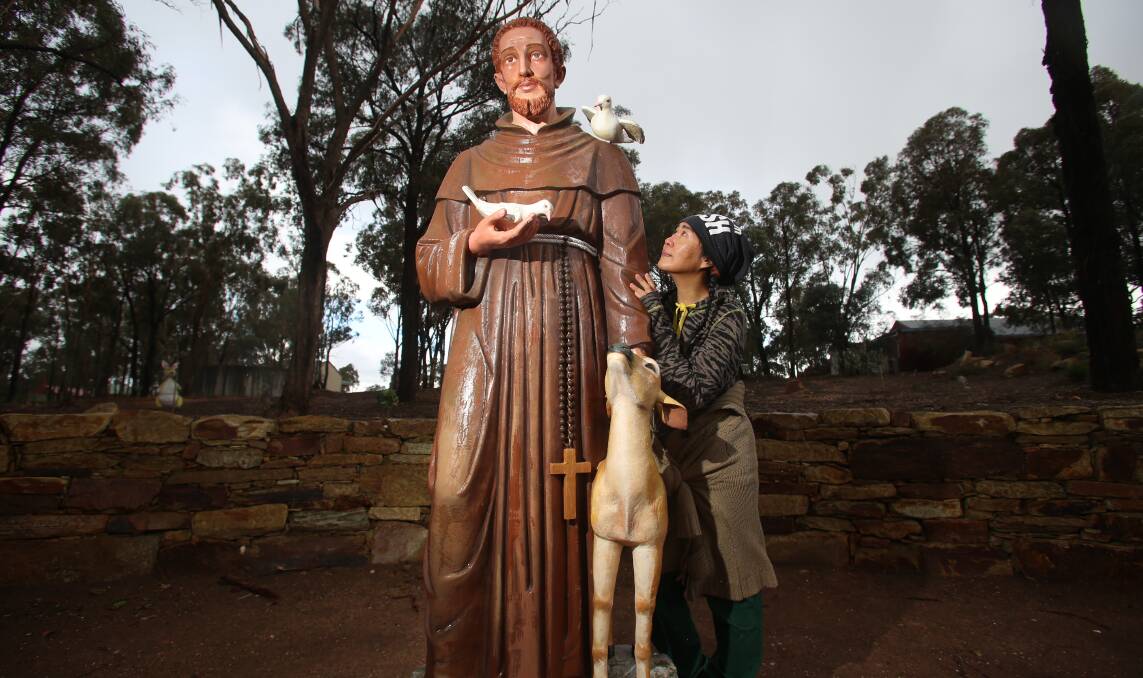 ADDITION: Artist Lucy Wang takes a closer look at the statue of St Francis of Assisi which is now part of the Peace Park at the Great Stupa pf Universal Compassion. Picture: GLENN DANIELS