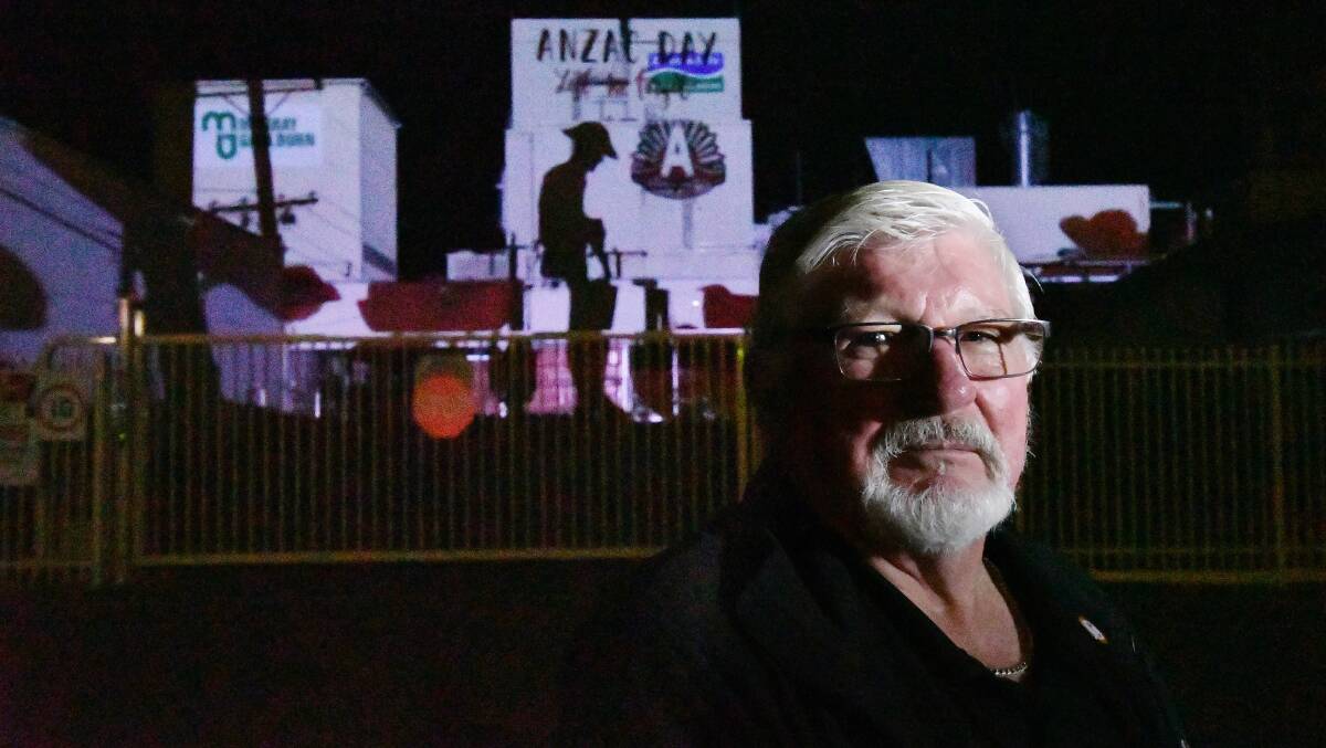 DISPLAY: Rochester RSL president Greg Walkley in front of a light projection will project onto a disused factory wall in Rochester for Anzac Day. Picture: DARREN HOWE