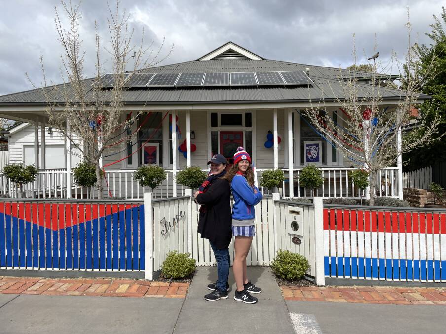 FAMILY RIVALRY Mother and daughter Kellie and Ella Flavell outside of their home which they decorated ahead of the AFL grand final. Picture: CHRIS PEDLER