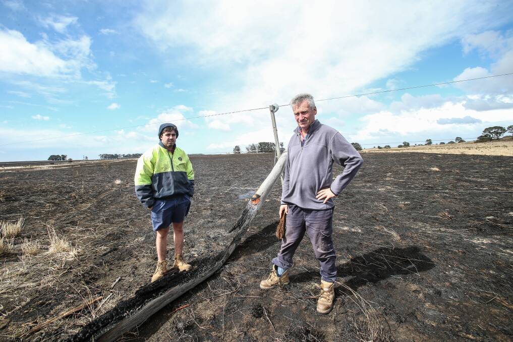 The Sisters farmers Jack Kenna Junior, left, and Bernie Harris with the power pole that started The Sisters/Garvoc bushfire on St Patrick's Day last year.