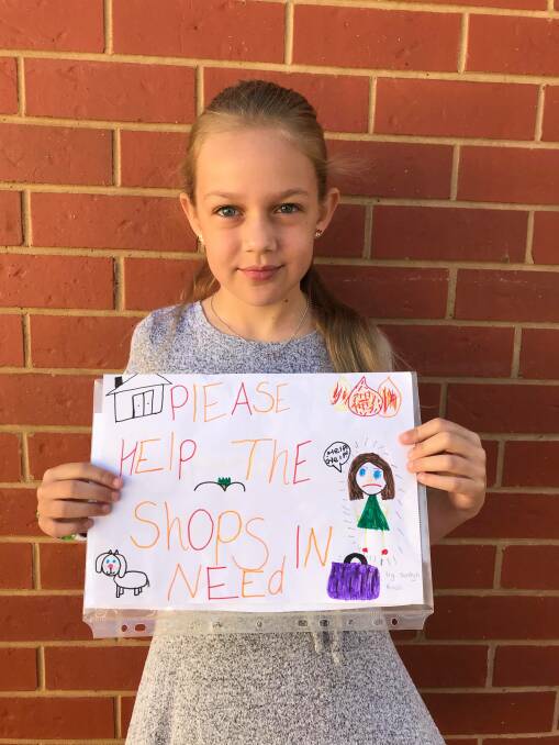 Leah Rinaldi's daughter Jordyn with the poster she created after hearing about the plight of small businesses in bushfire-affected communities. Picture: SUPPLIED