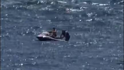 A passerby rescues a fallen jet ski rider near Windang Island, as seen in this still from footage taken by Jess Baird.