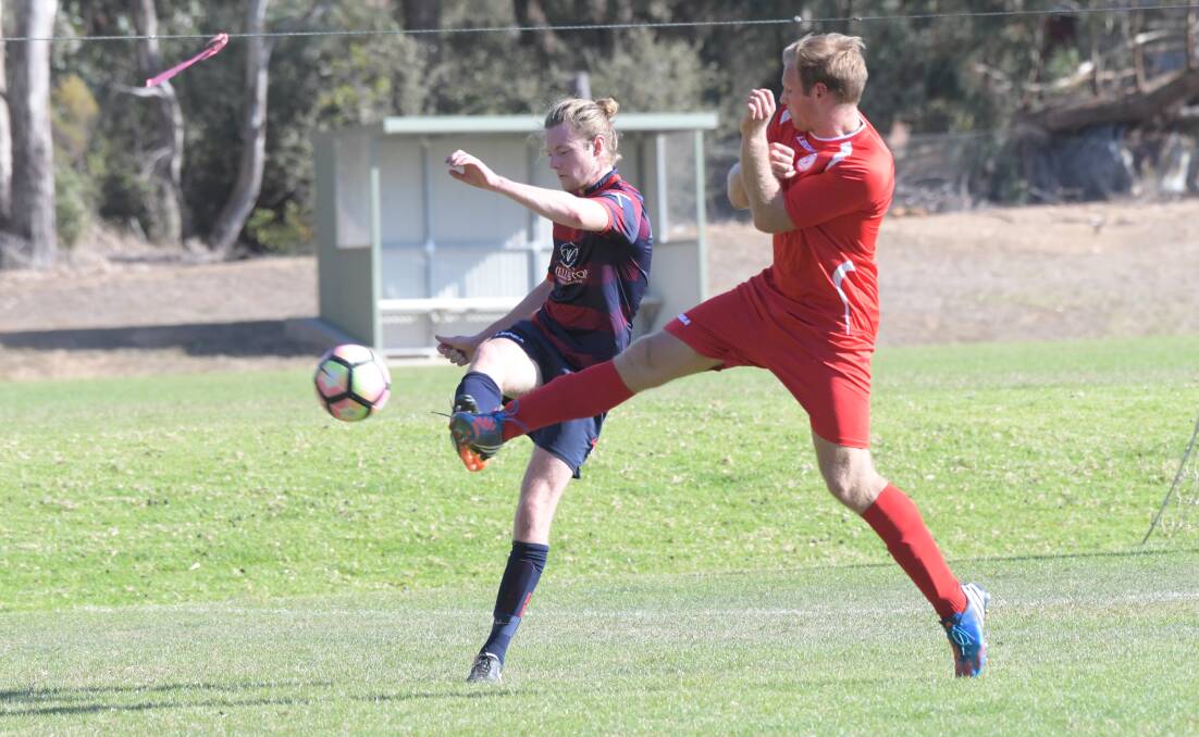 CLOSE-CHECKING: Epsom's Jack Kelly looks to get a clearing kick away despite pressure from Spring Gully United's Sam Walker. The Reds upset the Scorpions 2-1. Picture: NONI HYETT