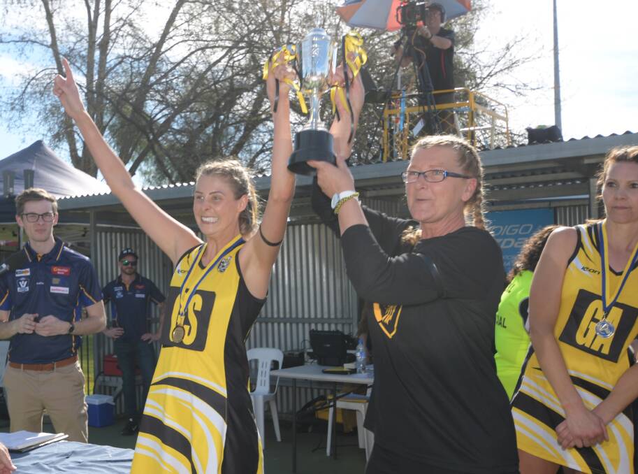 Dianne Guest-Oakley and Hayley Page hoist the A-reserve premiership cup after last September's victory over Kangaroo Flat. 