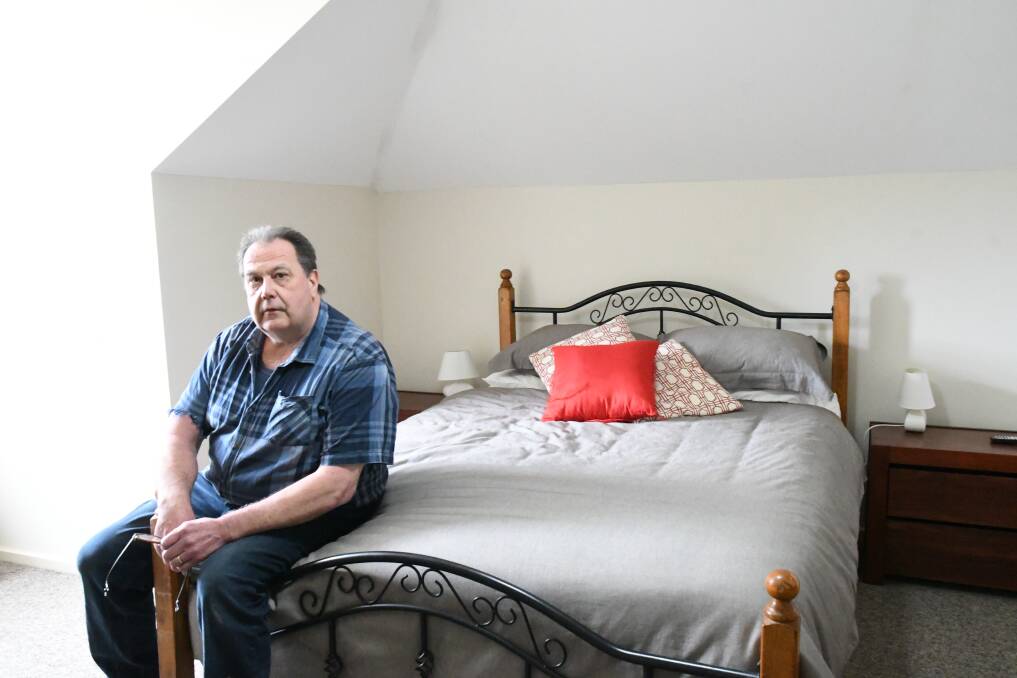 Darryl Peters sits on one of the beds in his two-room bed and breakfast. Neither rooms have ever been used due to sewerage and permit limitations. 