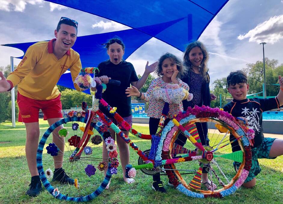Members of Golden Square Pool team under the 25 metres of new shade with their new yarn-bombed bike.
