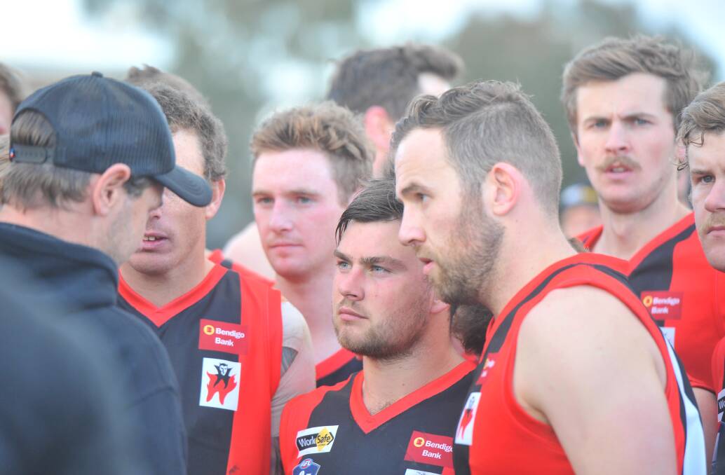 The Demons listen in to coach Brent Millar at the final change.