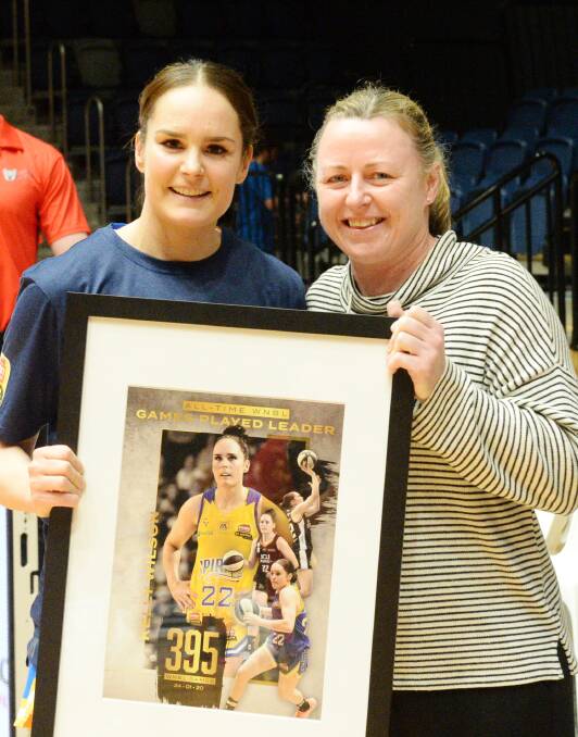 GREAT GUARDS: Kelly Wilson is presented with her WNBL record games trophy by Australian basketball great Kristi Harrower. Pictures: DARREN HOWE