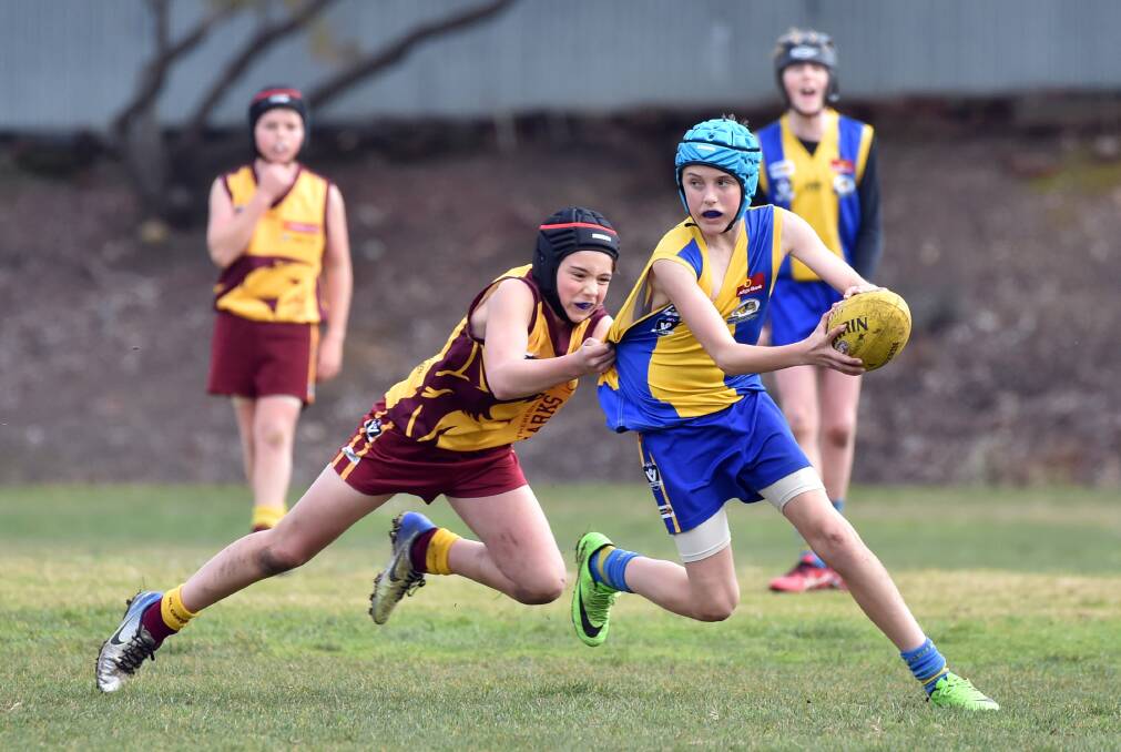 CAUGHT WITH THE BALL: Golden Square tries to work the ball forward despite the pressure of St Therese's in Saturday's under-12A match. Picture: GLENN DANIELS