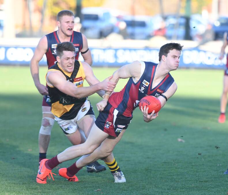 Sandhurst youngster Sean O'Farrell tries to fire out a handball against Kyneton. Picture: ADAM BOURKE