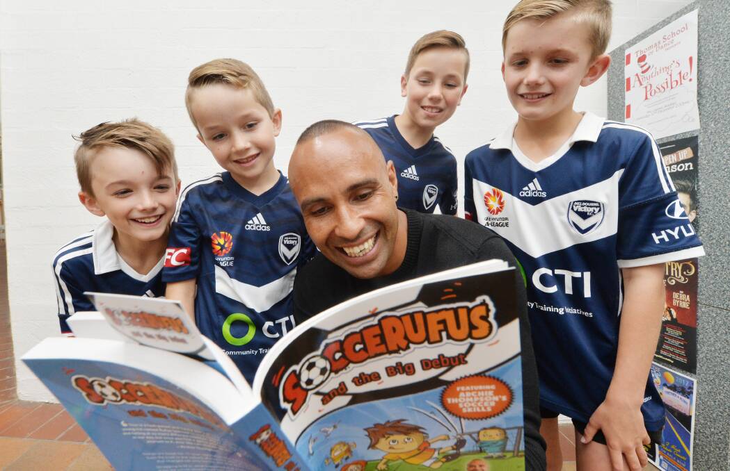 SOCCERUFUS: Melbourne Victory fans Hugo Fodor, Archie Lee, Fraser Lee and Jony Fodor reading the new book featuring Archie Thompson. Picture: DARREN HOWE 