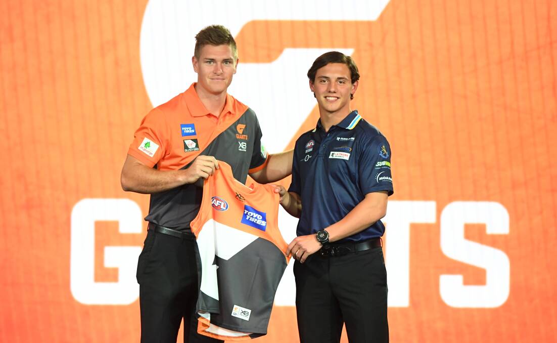 Jye Caldwell receives his GWS Giants jumper from the club's key defender Adam Tomlinson.